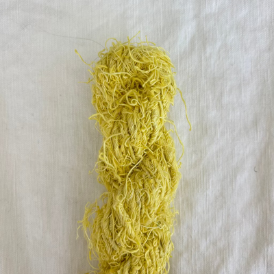 Yellow yarn skein on a light gray background