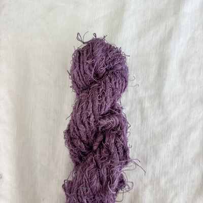 Purple skein of yarn on a light beige fabric background