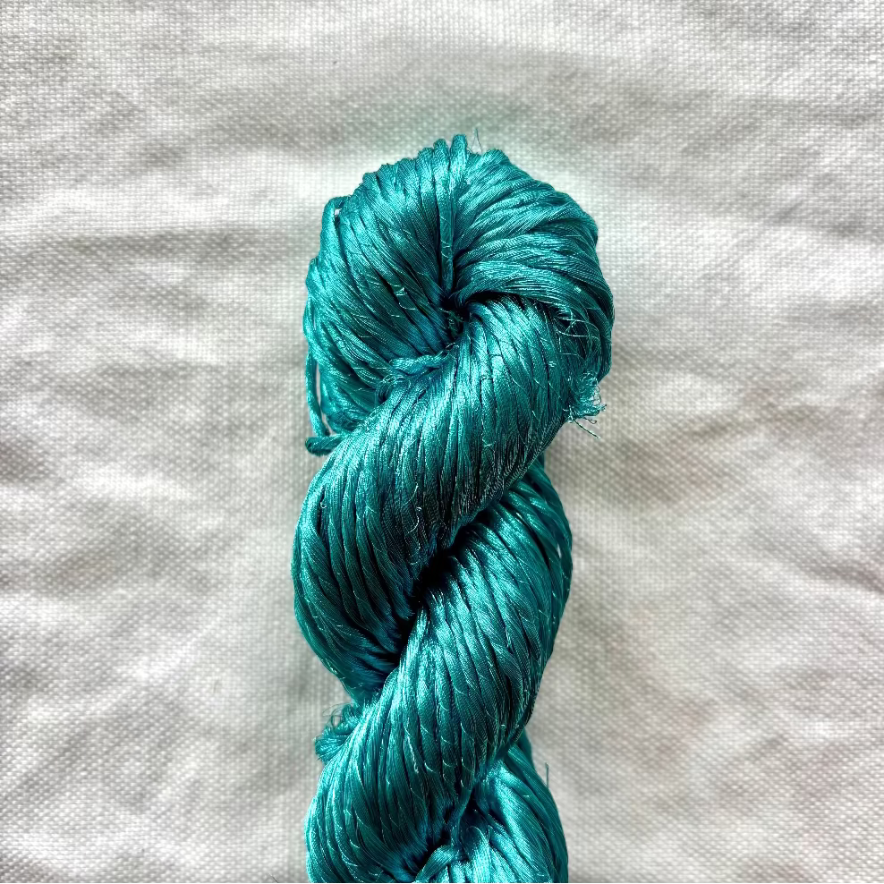 Turquoise skein of yarn on a textured white background