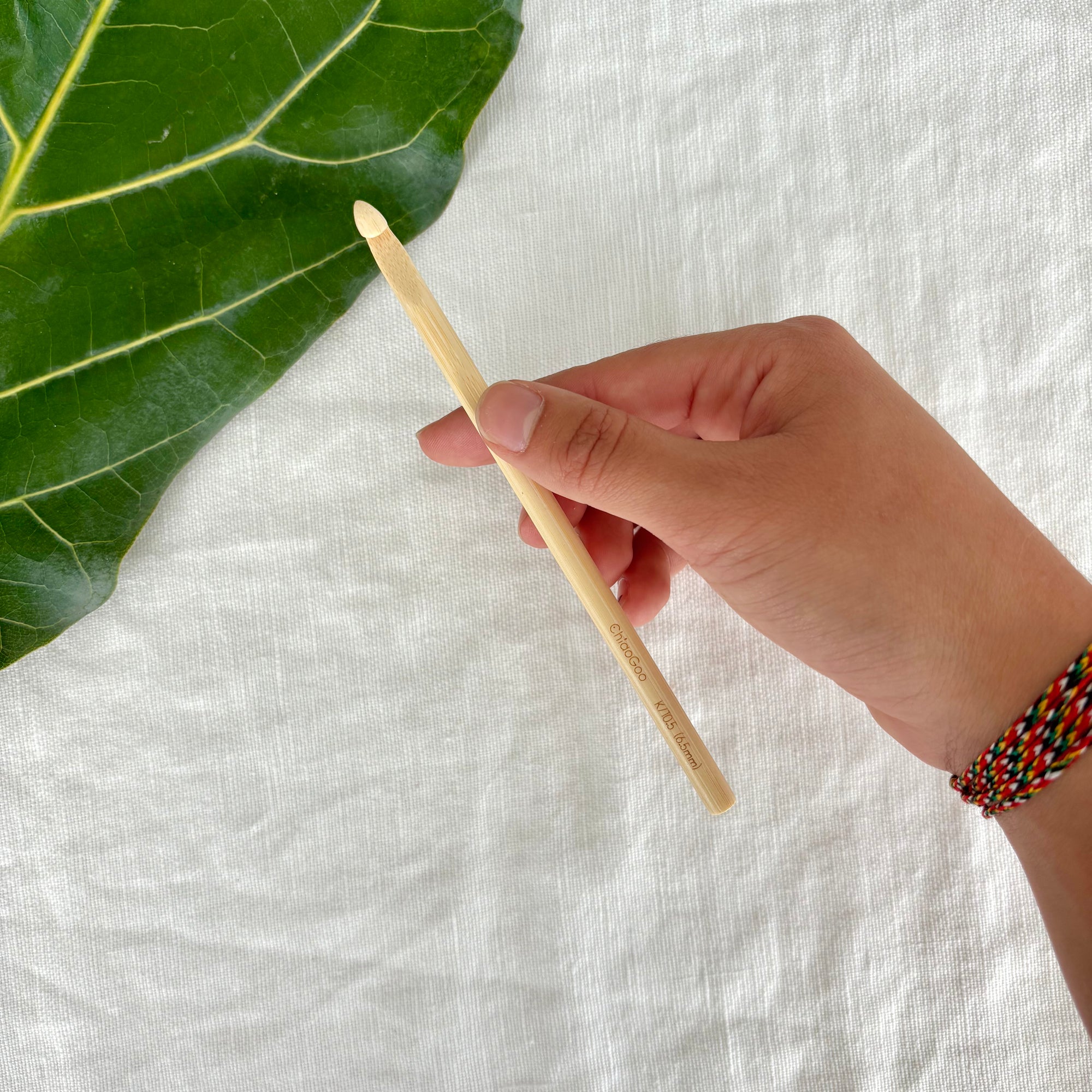 slim crochet hook on fabric and leafy background