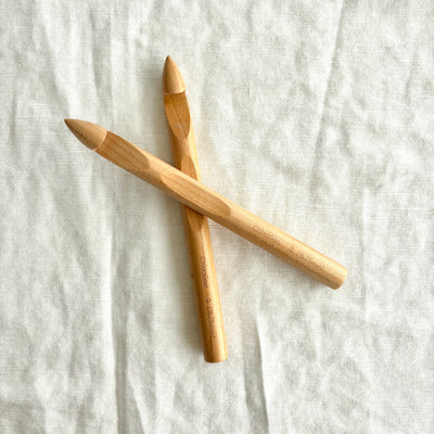 Two wooden crochet hooks on a textured white fabric background