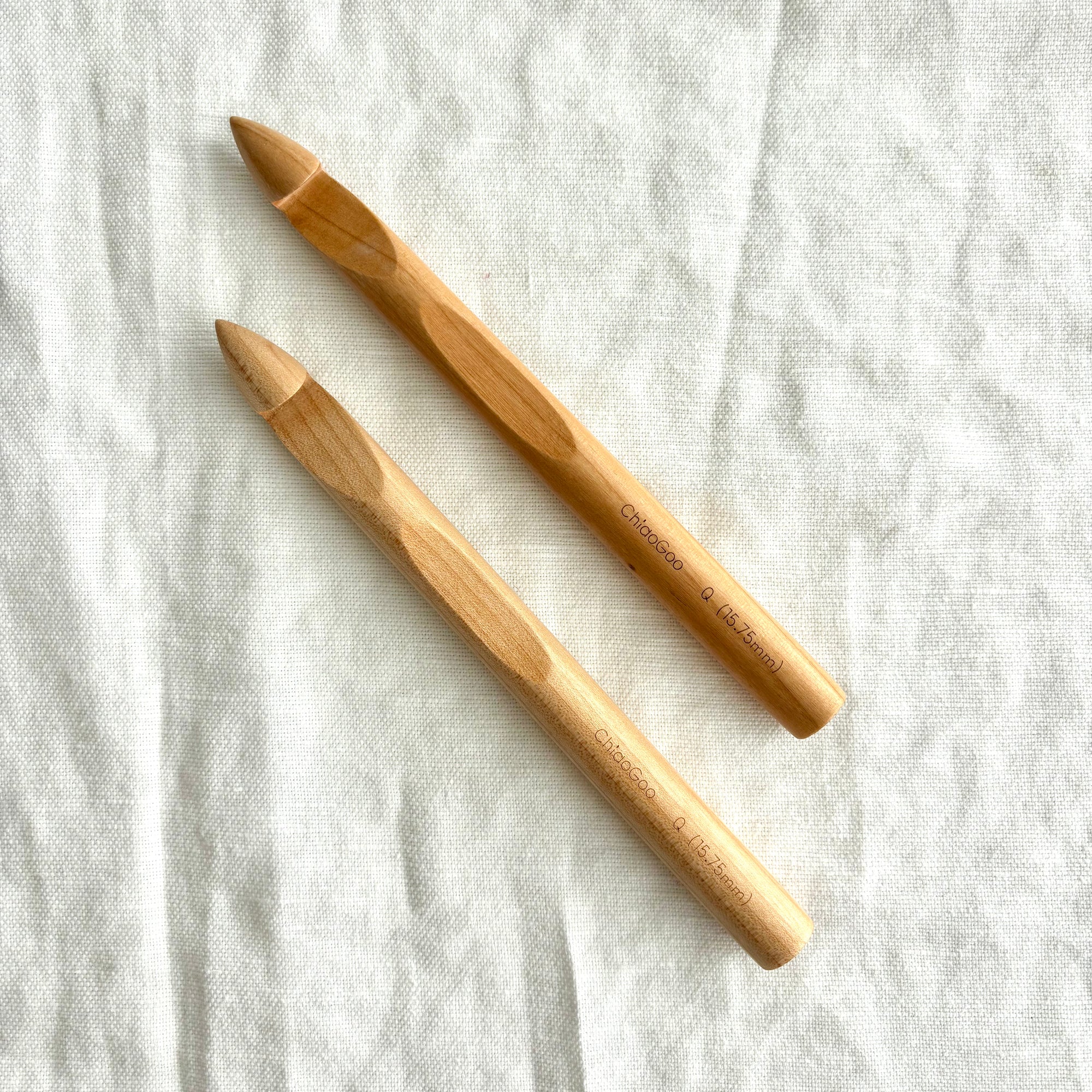 Two wooden crochet hooks on a light fabric background
