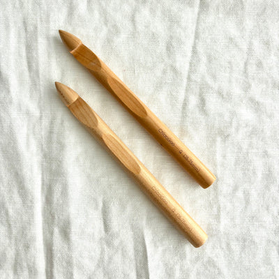 Two wooden crochet hooks on a light fabric background
