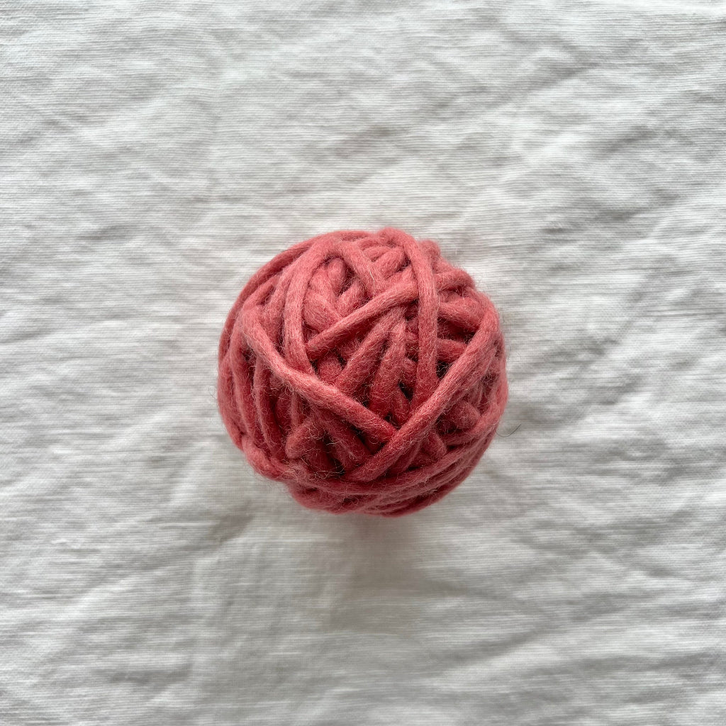 Ball of pink yarn on a textured gray background
