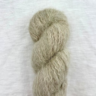 Hank of beige yarn on a textured white background