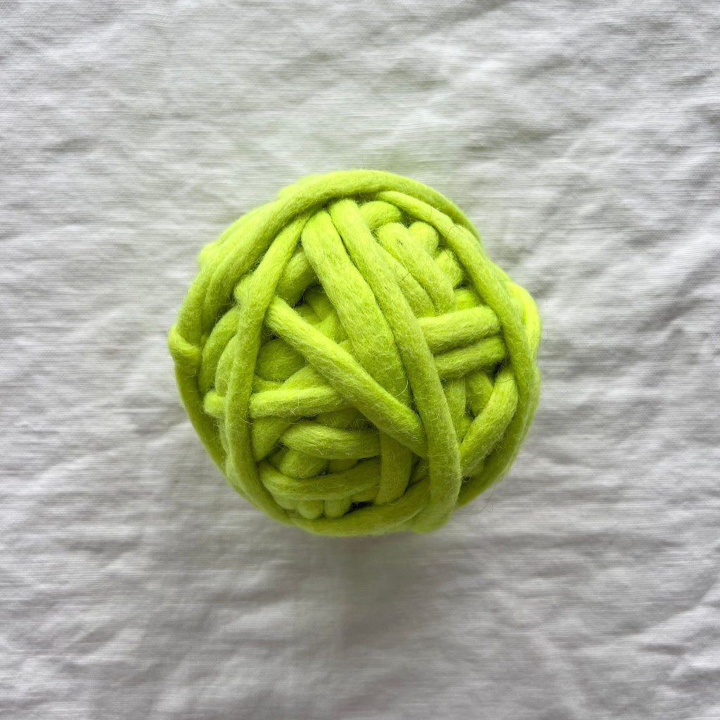 Green ball of yarn on a textured gray surface