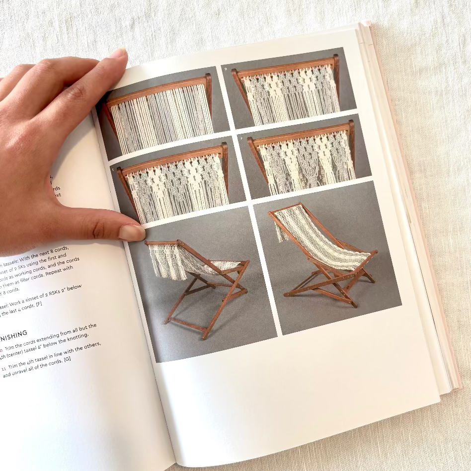 Open book showing a design for a wooden chair with fabric seat and backrest, held open by a hand.