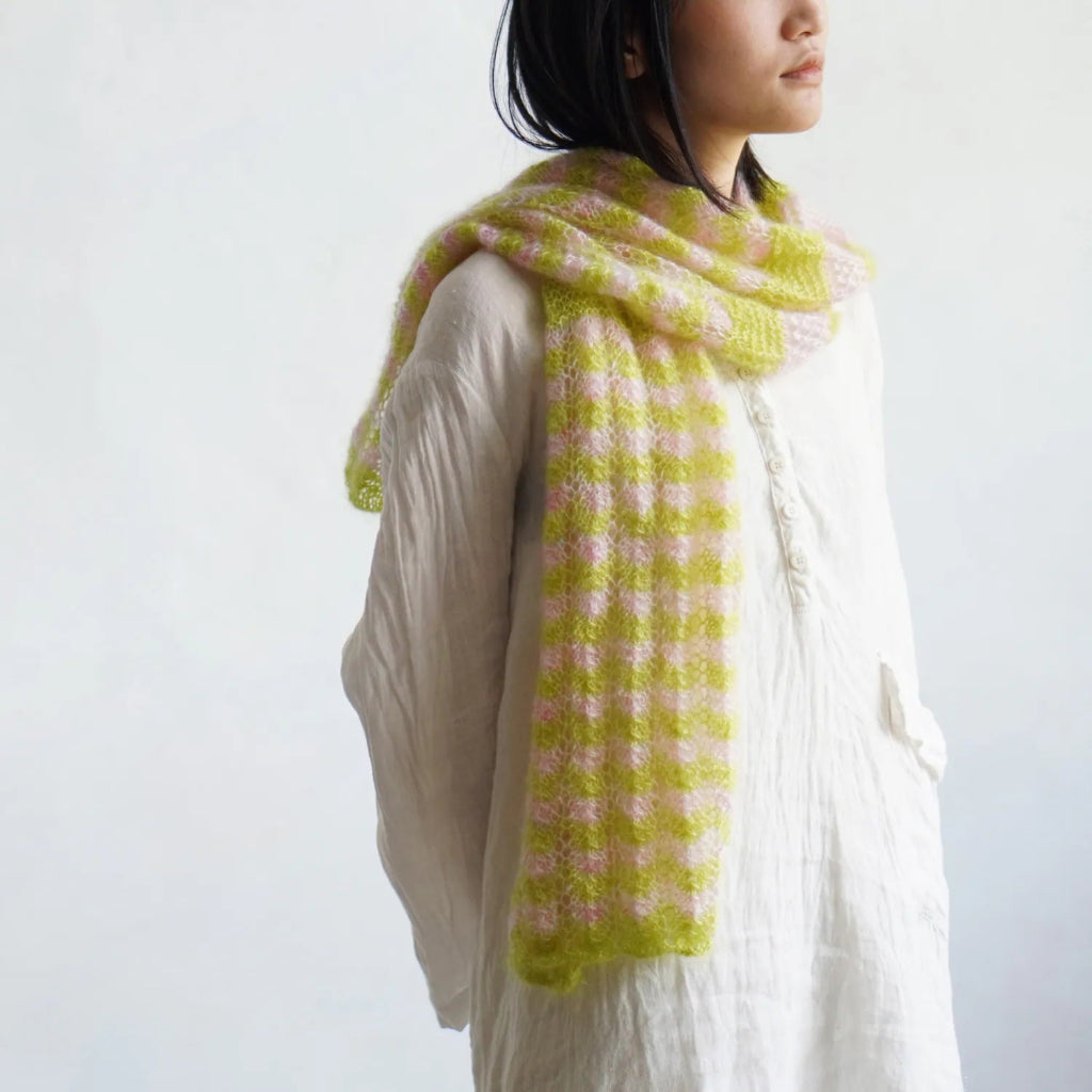 Person wearing a green and pink patterned scarf on a white background