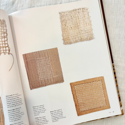 Open book showing fabric samples and text on a light background